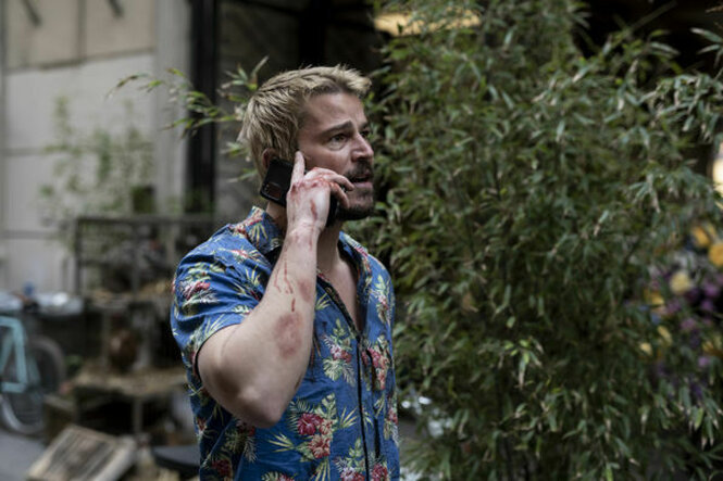Lucas Reyes (Josh Hartnett) steht mit Mobiltelefon neben einem Busch.