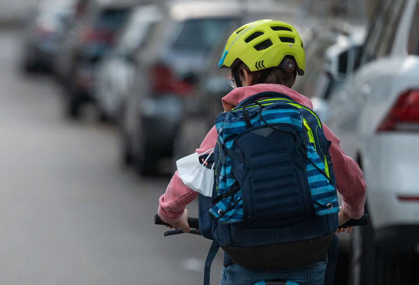 Ein Schulkind fährt mit seinem Fahrrad eine Straße entlang