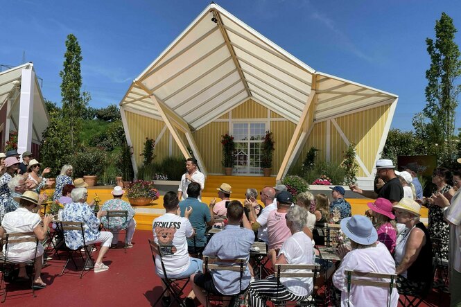 Ein Mann steht vor einem Pavillon und unterhält sein Publikum