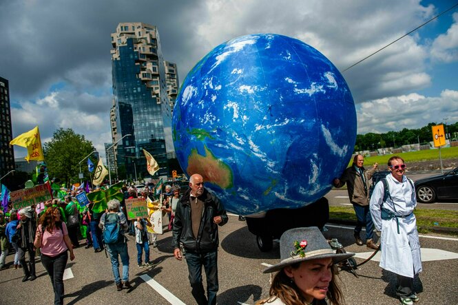 Demonstranten neben einer großen aufgeblasenen Weltkugel
