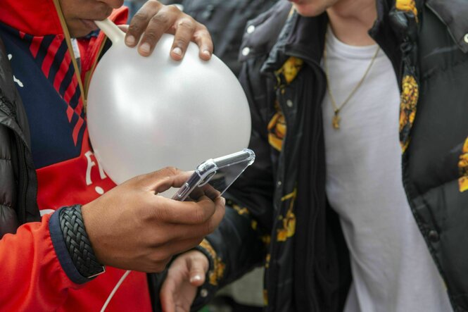 Jugendliche konsumieren Lachgas mit einem weißen Ballon