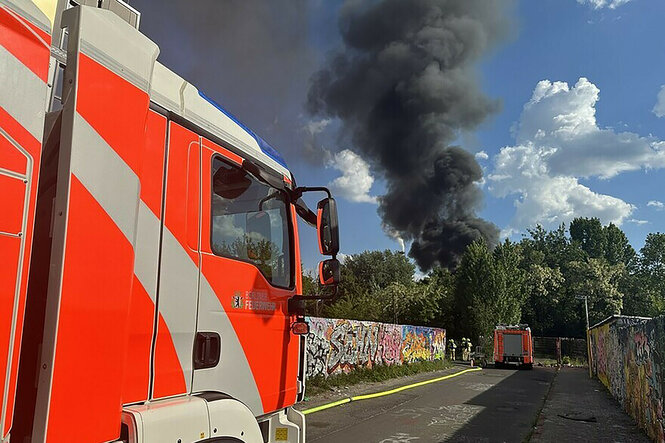 Ein Löschzug der Feuerwehr trifft am Einsatzort ein, nachdem in einer Kleingarten-Kolonie ein Feuer ausgebrochen ist. Mehrere Gartenlauben stehen in Flammen