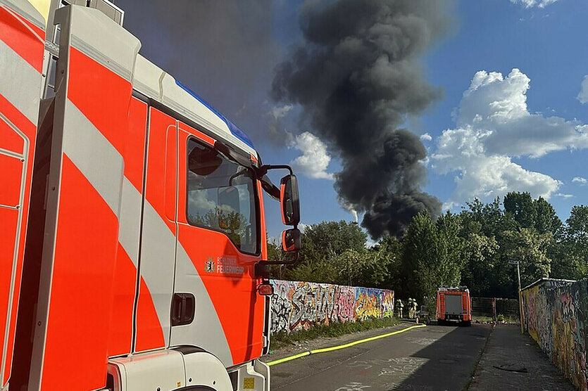 Ein Löschzug der Feuerwehr trifft am Einsatzort ein, nachdem in einer Kleingarten-Kolonie ein Feuer ausgebrochen ist. Mehrere Gartenlauben stehen in Flammen