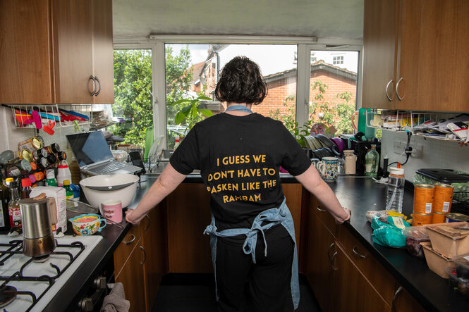 Porträt von Yehudis Fletcher in ihrer Küche, ihr Shirt mit Aufdruck von hinten fotografiert.