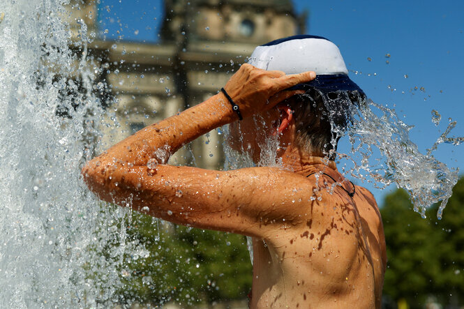 Ein Mann kühlt sich an einem heißen Sommertag in einem Brunnen ab