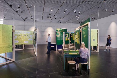 Ein Raum in der Ausstellung "Die Nazis waren ja nicht einfach weg". Menschen stehen vor aufgestellten Tafeln.