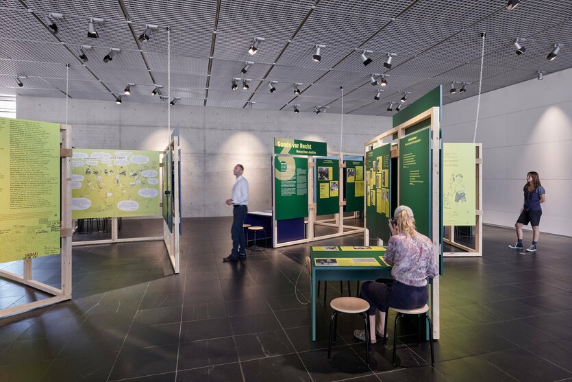 Ein Raum in der Ausstellung "Die Nazis waren ja nicht einfach weg". Menschen stehen vor aufgestellten Tafeln.