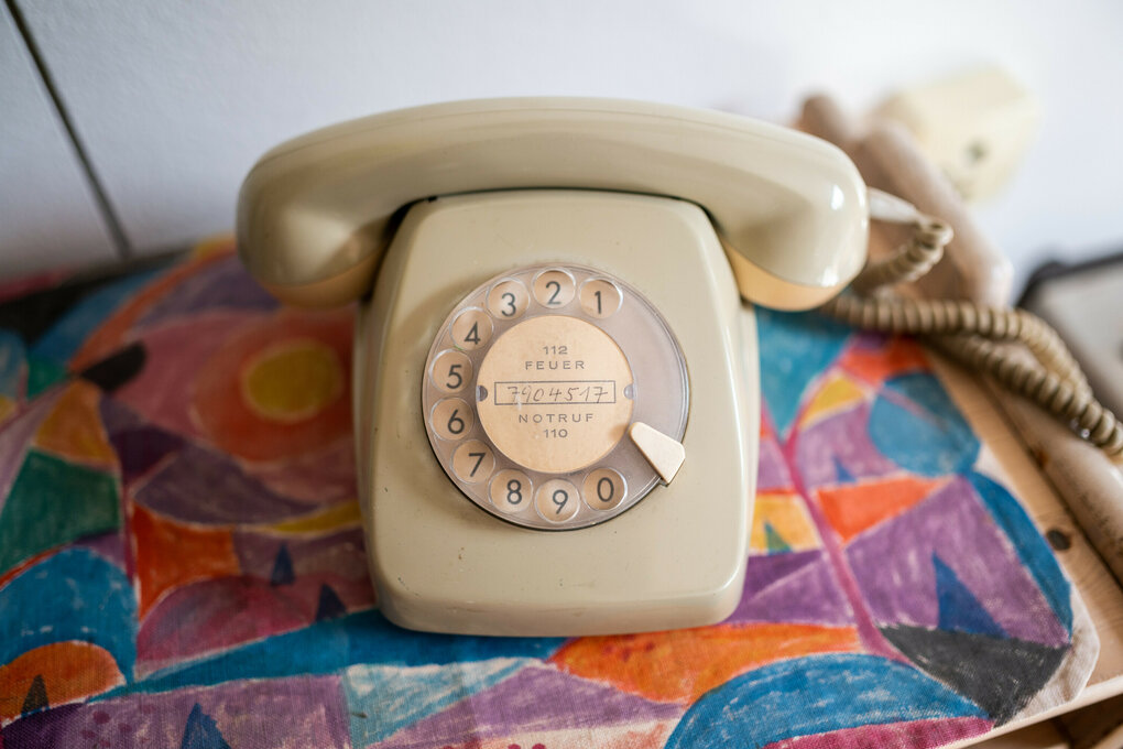 Ein Telefon aus den 60er Jahren steht auf einer bunten Decke.