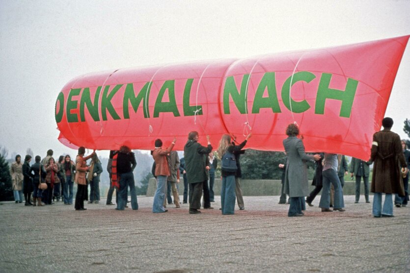 Menschen halten ein Transparent hoch. Darauf steht "Denkmal nach"