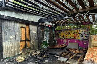 Verkohlte Balken vor einer Graffitiwand