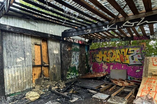 Verkohlte Balken vor einer Graffitiwand