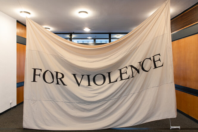 Ein weißes Tuch auf dem mit schwarzen Buchstaben steht:"FOR VIOLENCE"