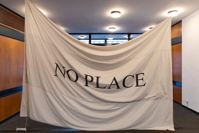 Ein weißes Tuch auf dem mit schwarzen Buchstaben steht:"NO PLACE"