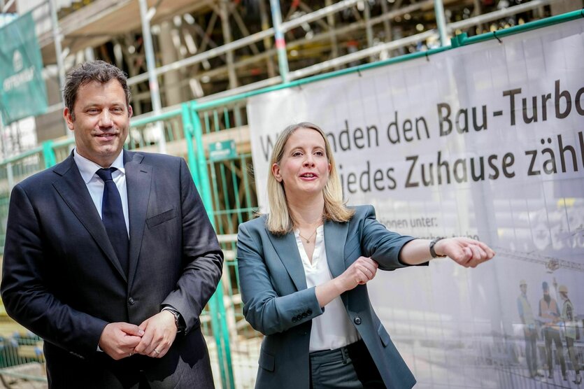 Verena Hubertz (SPD) steht mit Lars Klingbeil am Rand einer Baustelle, ein Transparent verkündet den Bau-Turbo und sie krempelt die Ärmel hoch