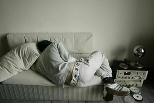 Ein junger Mann schläft auf einem Sofa, das viel zu klein für ihn ist