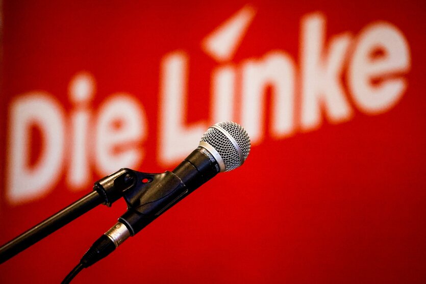 Das Bild zeigt ein Mikrophon ohne Mensch dabei vor einem Hintergrund mit dem Schriftzug "Die Linke".