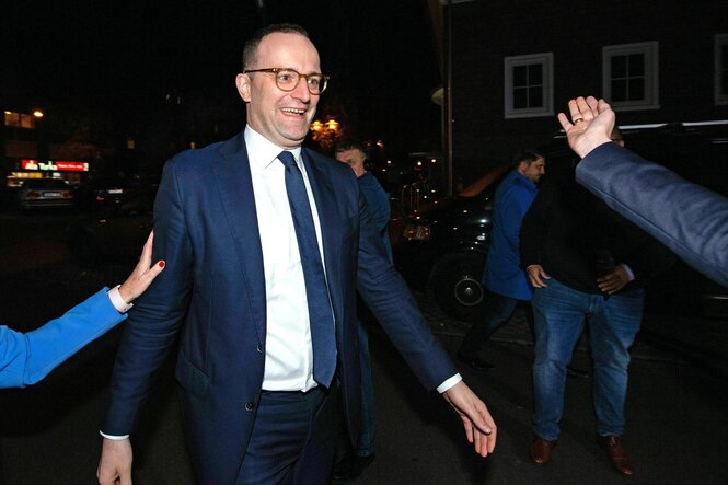 Jens Spahn läuft mit einem Lächeln im Gesicht durch die Nacht, Hände werden ihm entgegengestreckt