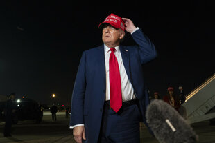 Der US-Präsident Donald Trump steht im blauen Anzug und mit roter Basballkappe vor einem Mikrofon