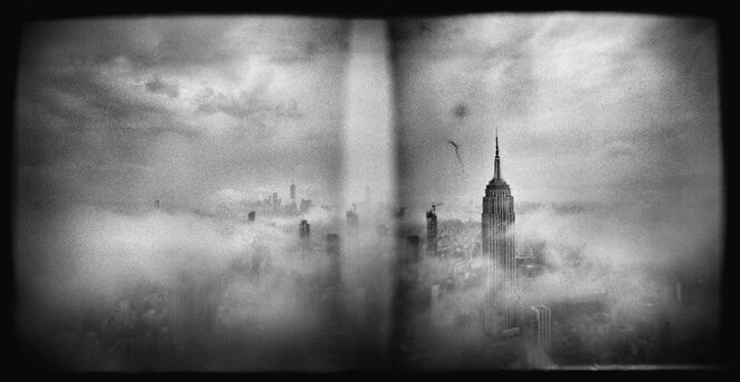 Schwarz-Weiß-Fotografie von New York City, auf der die Wolkenkratzer der Stadt zu sehen sind. Sie sind in Nebel gehüllt. Die Ränder der Fotografie sind vignettiert.