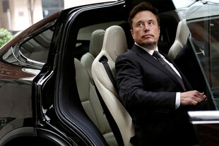 Elon Musk sitzt bei geöffneter Tür auf der Hinterbank eines Teslas