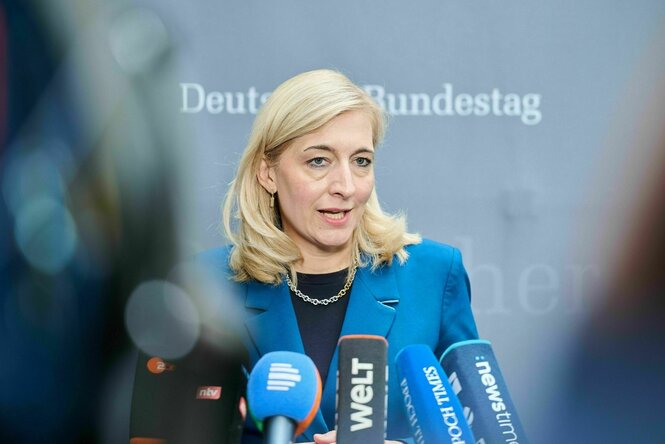 Eine Frau mit blauer Jacke spricht zu Vertretern der Presse
