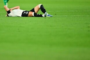 Eine Fußballerin im DFB-Trikot liegt verletzt am Boden