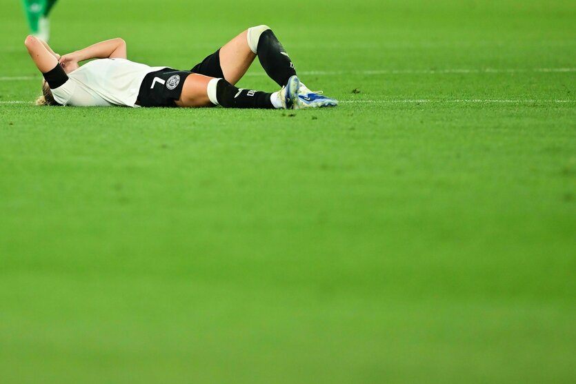 Eine Fußballerin im DFB-Trikot liegt verletzt am Boden