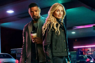 Das Filmplakat von „Back in Action“ zeigt zwei Personen, die im türkis-violetten Neonlicht einer Tankstelle steht: Die Schauspielerin Cameron Diaz trägt blondes, gewelltes Haar und eine dunkle Lederjacke, der Schauspieler Jamie Foxx eine graue Lederjacke und kurz geschorene Haare. Er hält einen Coffee-to-go-Becher.