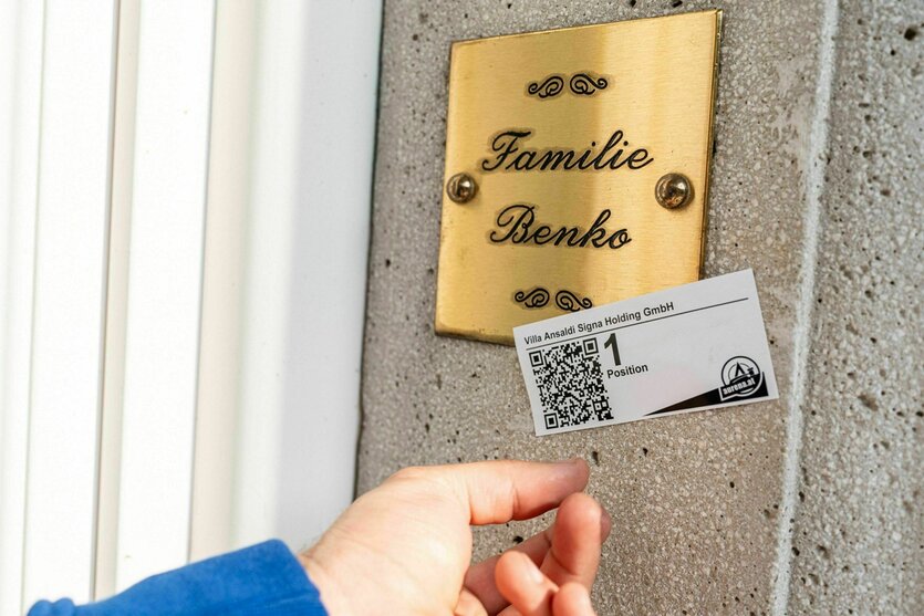 Ein Aufkleber mit einem QR Code klebt auf einem Klingelschild mit dem Namen Benko