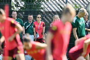 Julia Gwinn steht auf Krücken am Rand eines Trainingsplatzes