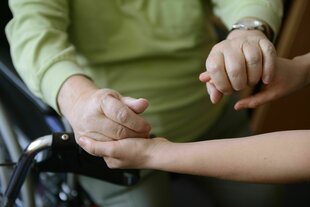 Zwei Personenen halten sich an den Händen
