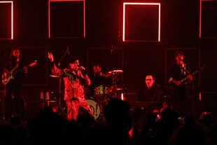 Eine Band auf der Bühne, in rotes Licht getaucht