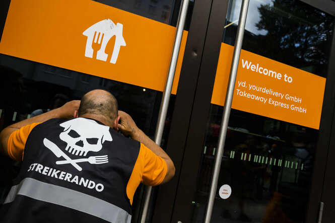 Fahrer vor der Lieferando-Zentrale: Er trägt eine Weste mit Totenkopf und der Aufschrift Streikerando
