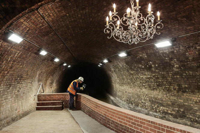 Ein Blick in einen Tunnel der Kanalisation, ein Kronleuchter hängt im Vordergrund