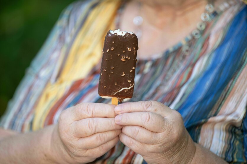 Eine ältere Person hält ein Eis am Stiel in der Hand