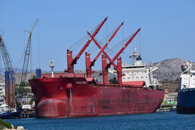 Ein Schiff, ausgestattet mit vier mächtigen Kränen, liegt in einem Hafen