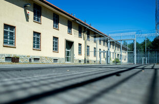 Ein Gebäude, umringt von Stacheldrahtzäunen, die Fenster vergittert