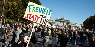 Viele Menschen auf einer Straße, einer hat ein Schild mit der Aufschrift "Freiheit statt TTIP", im Hintergrund das Brandenburger Tor (Berlin)