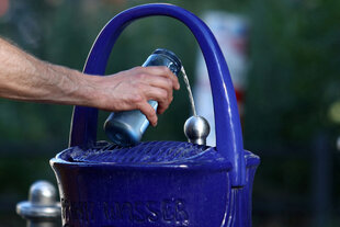 eine Person füllt eine Wasserflasche auf
