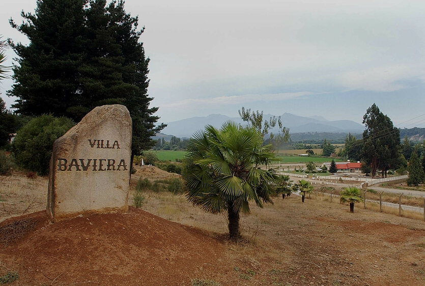 Auf einem Feldstein vor einem großen Gelände steht der Schriftzug "Villa Baviera"