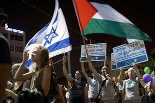 Demonstranten schwenken bei einer Friedensdemonstration israelische und palästinensische Flaggen