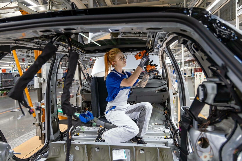 Eine junge Frau montiert an einem Fahrzeug