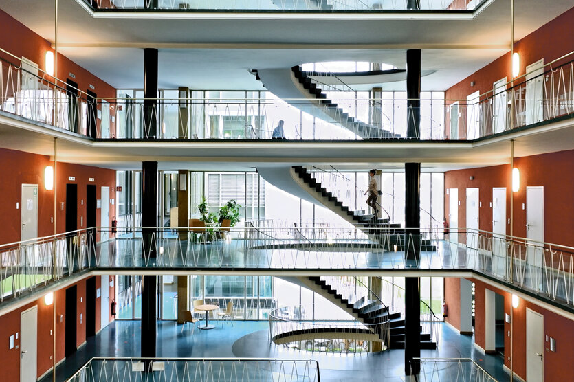 Blick in einen drei Stockwerke umfassenden Lichthof mit umlaufenden Galerien und freischwebenden Treppen