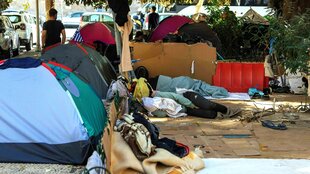 Obdachlos: kleine Zelte stehen auf dem Gehweg, der Boden ist mit Pappe abgedeckt, zwei Menschen schlafen