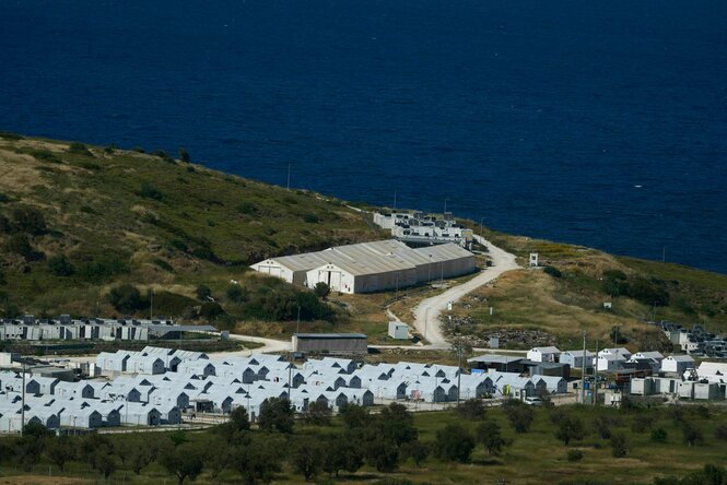 Blick von oben auf das umzäunte Geflüchtetenlager Kara Tepe. viele kleine Container stehen auf einer Wiese, weiter unten zwei langgestreckte Gebäude