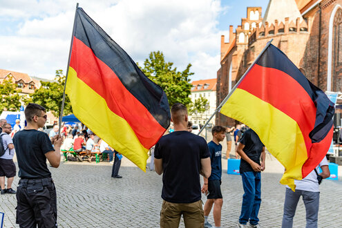 Mitglieder der Jungen Alternative, der Nachwuchsorganisation der AfD, schwenken auf einer Wahlkampfveranstaltung der AfD Brandenburg in Cottbus Deutschlandfahnen.