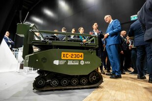 Friedrich Merz lässt sich ein ferngesteuertes Transportfahrzeug bei der Wiederaufbaukonferenz für die Ukraine erklären