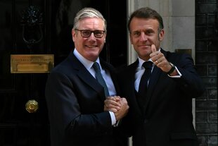 Keir Starmer empfängt Emmanuel Macron, beide schauen in die Kamera und lächeln, Macron reckt den Daumen hoch