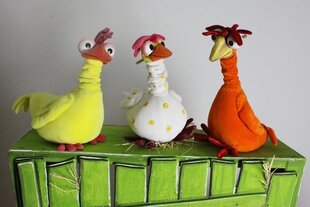 Drei bunte Stoffhühner (gelb, weiß, orange) sitzen auf einem grünen Kasten