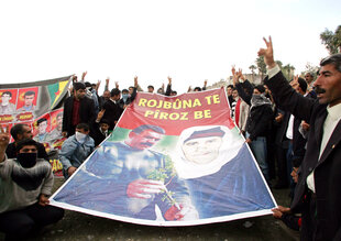Archiv: Kurdische Männer zeigen ein Transparent mit dem Bild des inhaftierten kurdischen Rebellenführers Abdullah Öcalan und seiner Mutter Fatma Öcalan, auf dem der Slogan „Happy Birthday“ zu lesen ist, und schwenken V-Siegeszeichen